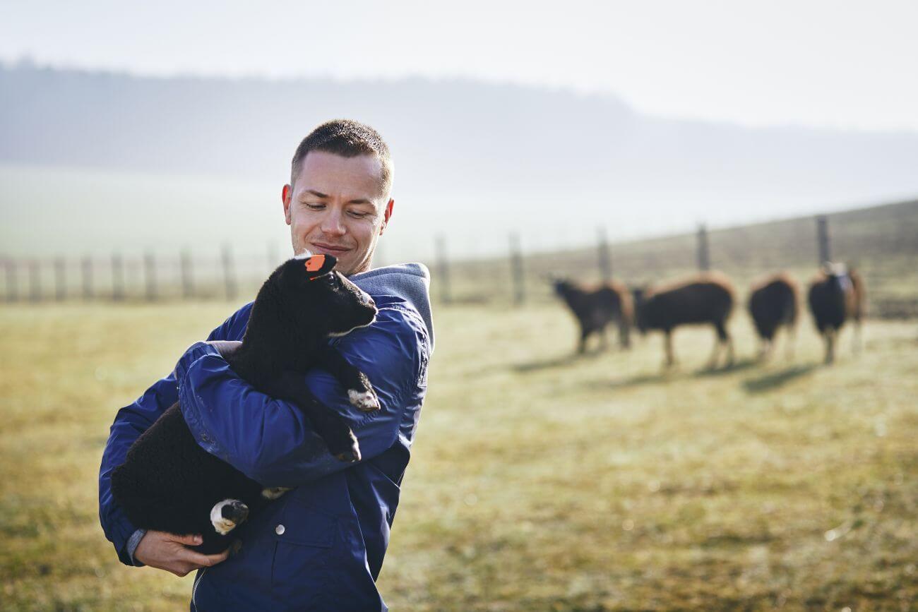 młody rolnik 2022 mężczyzna trzyma kozę